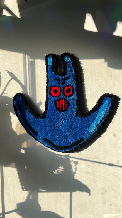 a rug hanging on a wall featuring the design of Man Ray's mask from Spongebob